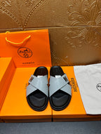 Hermes sandals with light gray textured cross straps, black footbed, H buckle