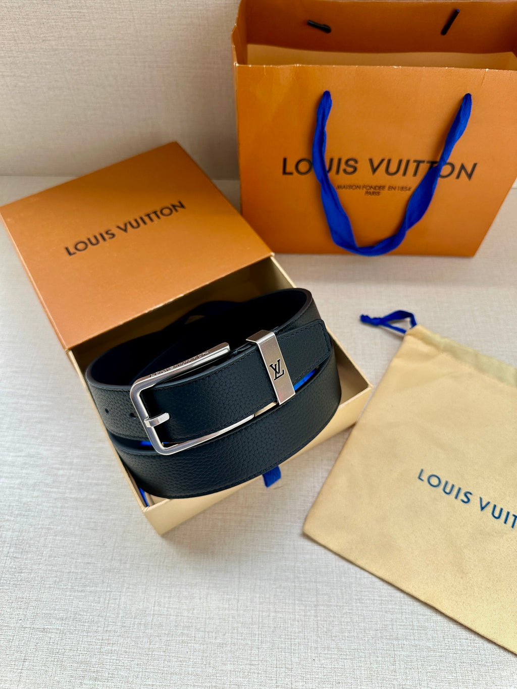 Louis Vuitton belt in dark blue leather with silver-toned buckle in box.