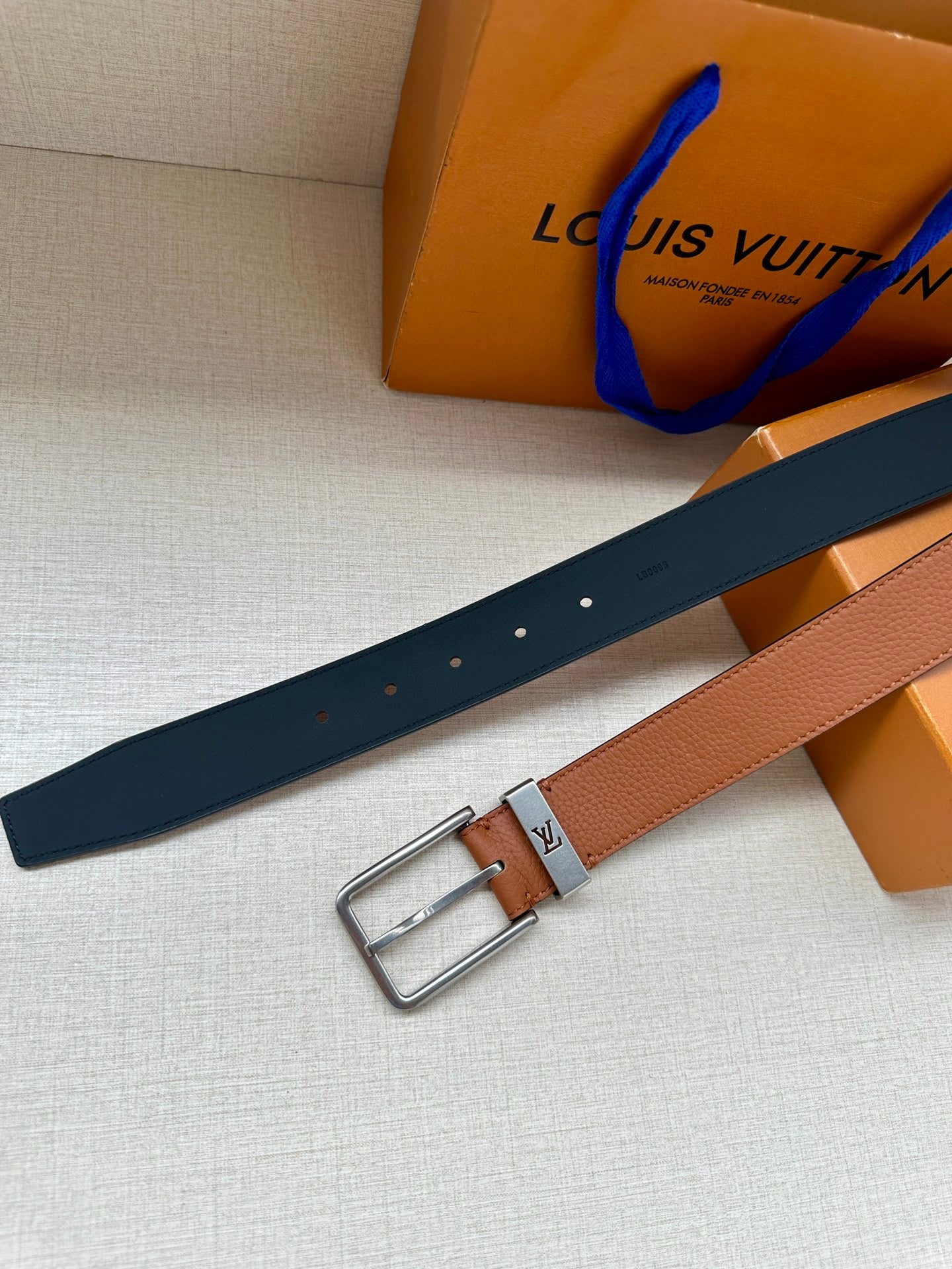 Louis Vuitton leather belt with dark navy strap, tan panel, and silver buckle