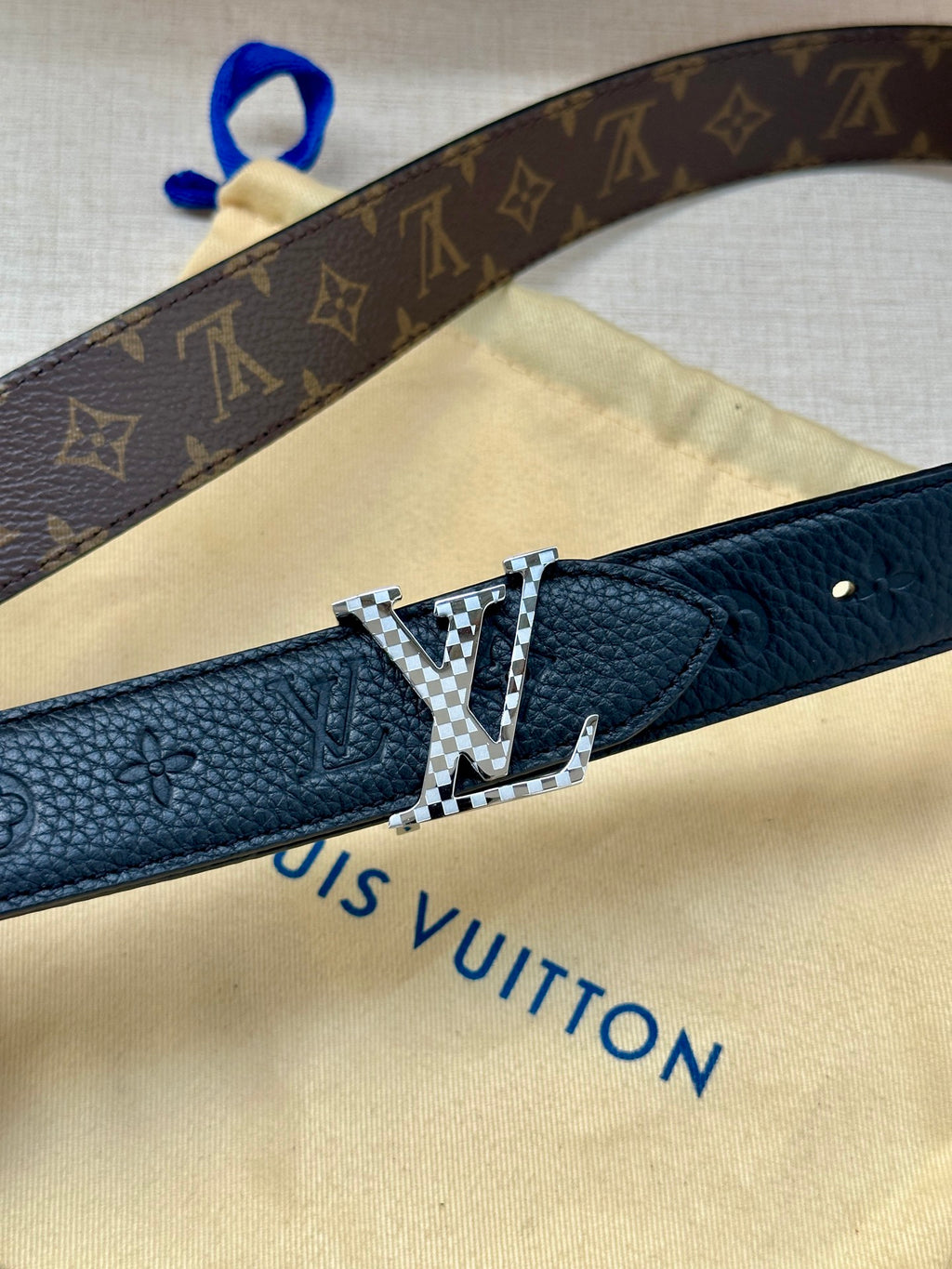 Dark blue leather belt close-up: engraved LV buckle on textured strap