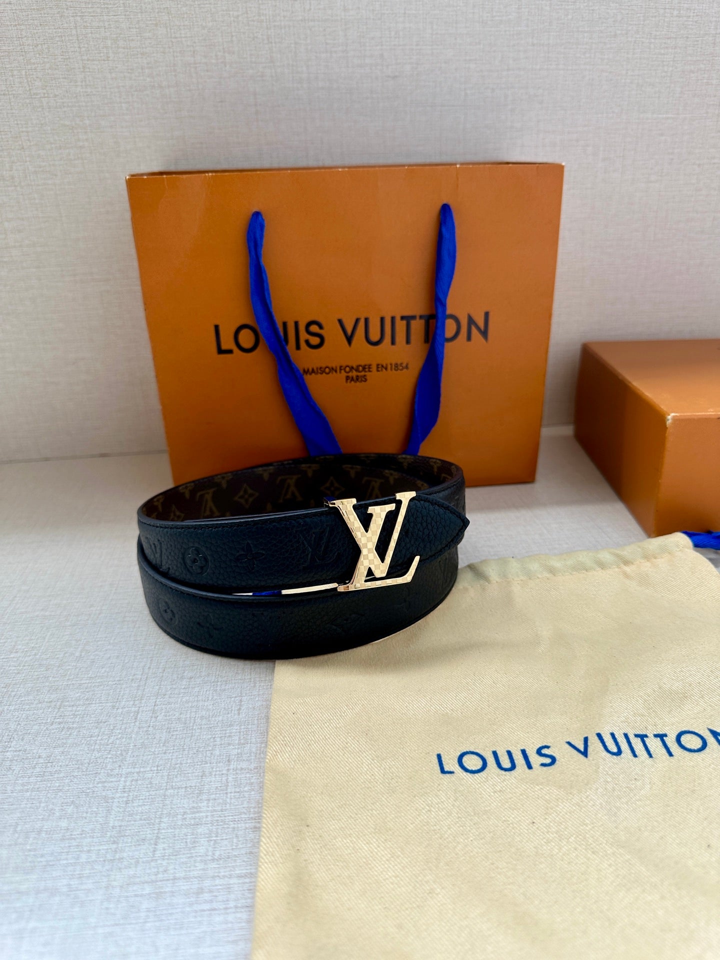 Dark blue leather belt with LV buckle and monogram pattern on display