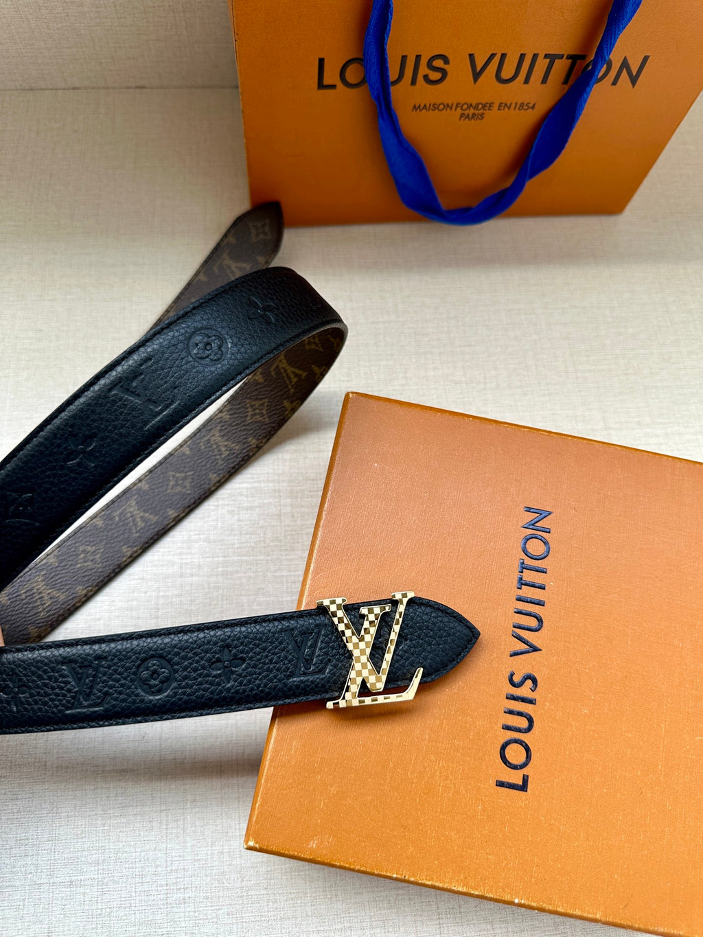 Dark blue leather belt with LV buckle and monogram trim, angled view