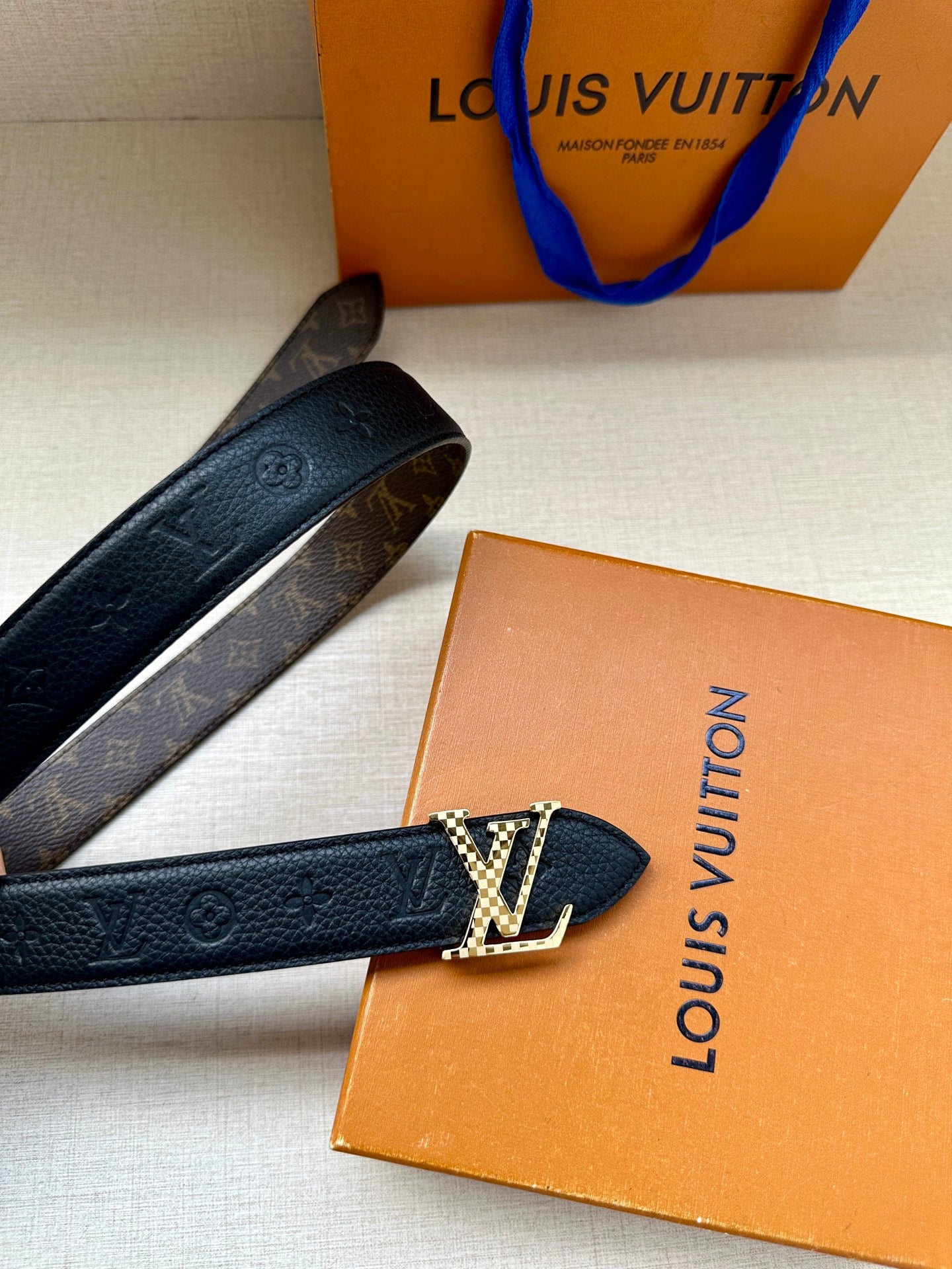 Dark blue leather belt with LV buckle and monogram trim, angled view