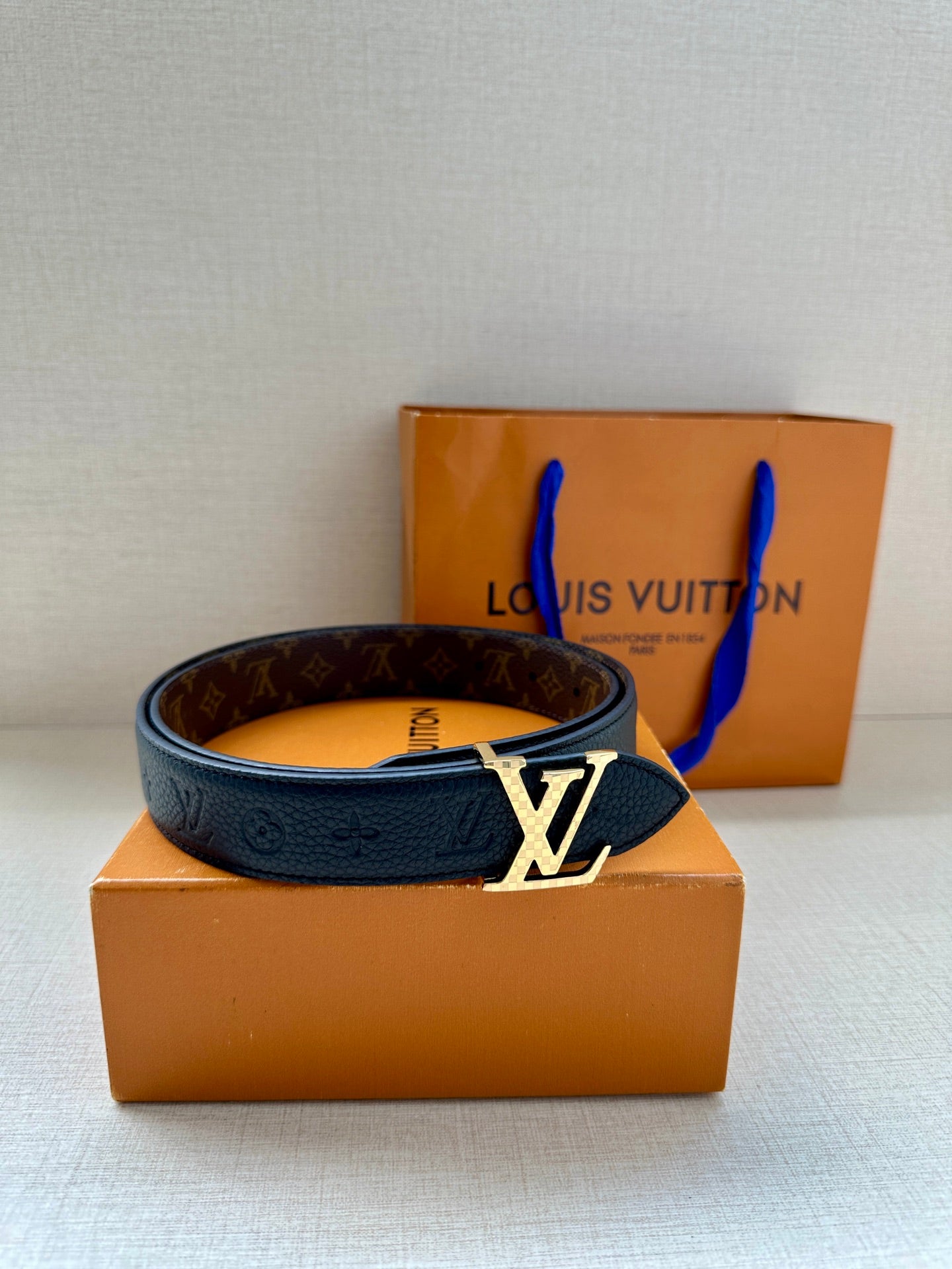Dark blue leather belt with gold-toned LV buckle and monogram strap