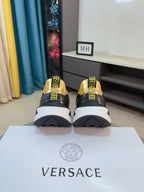 Heel view of black sneakers with gold logo detailing and chunky white sole.