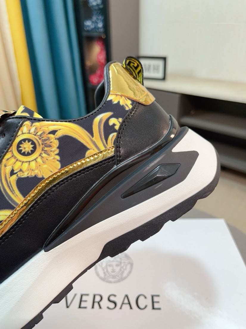 Side view of black lace-up sneakers with gold baroque print and round emblem on upper.