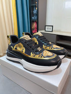 Pair of black lace-up sneakers with gold baroque graphics, Medusa-style emblem, white sole.