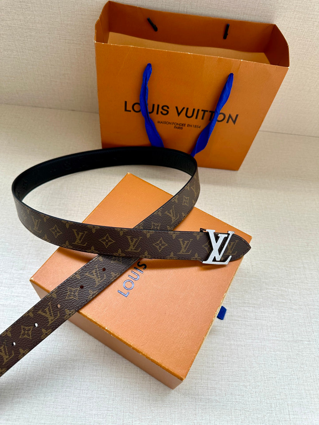 Monogram belt with dark strap and gold-tone LV buckle with orange box insert
