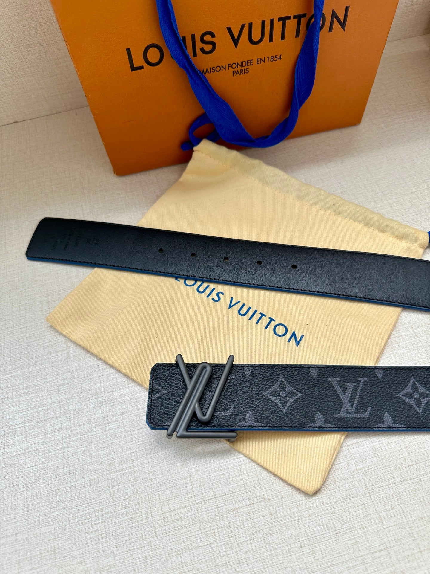 Louis Vuitton belt strap with dark monogram leather and silver buckle on blue edge