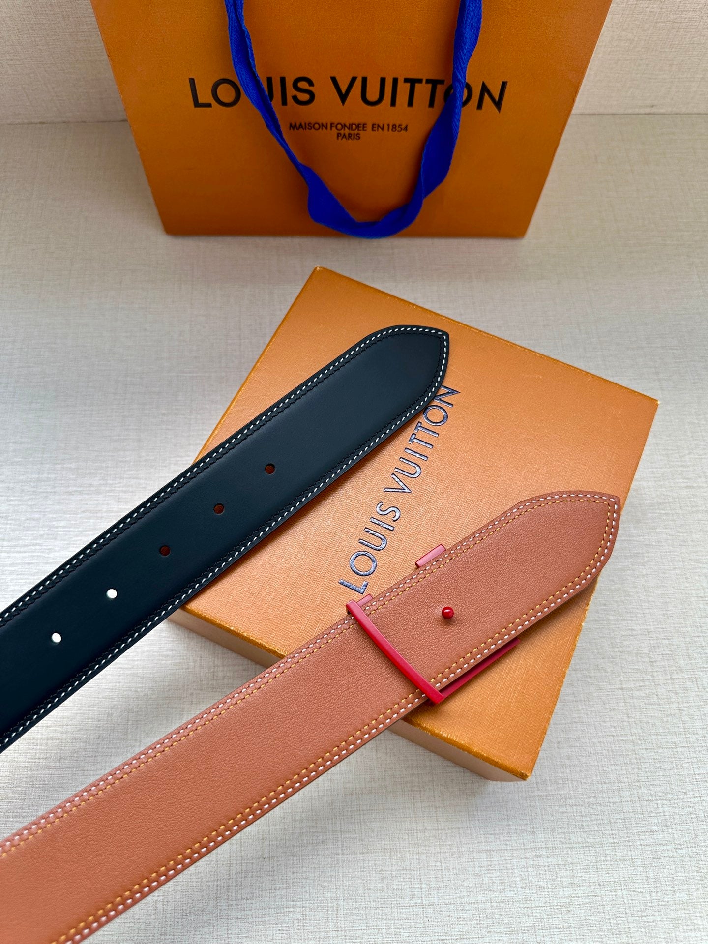Dark blue and tan leather belts with LV monogram buckles, stud details