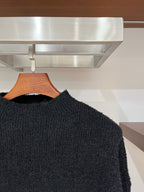 Dark textured long-sleeve sweater with crew neck, side view on hanger