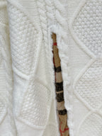 Cream cable-knit sweater with plaid inner placket and exposed inner fabric