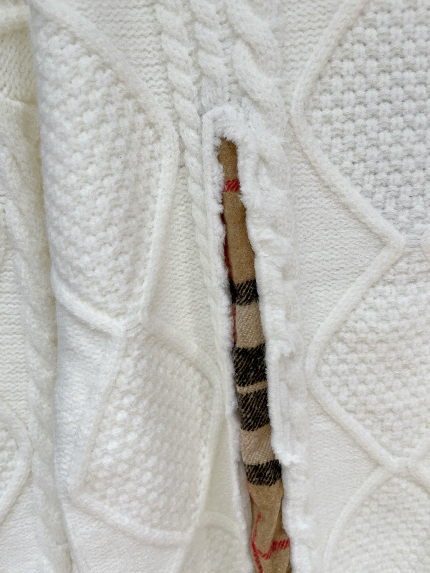 Cream cable-knit sweater with plaid inner placket and exposed inner fabric