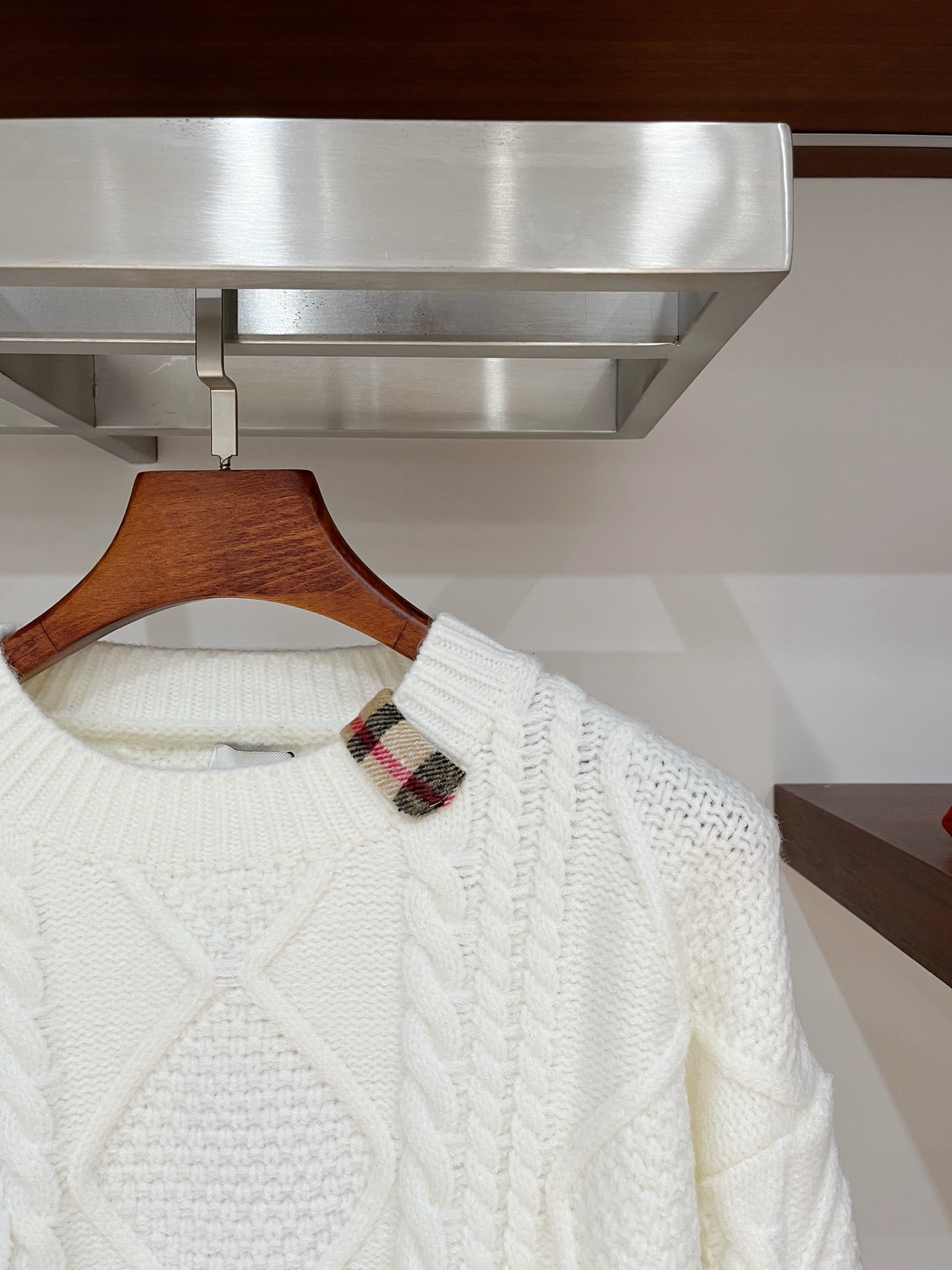 Cream cable-knit sweater close-up at neckline with plaid inner collar