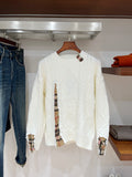 Cream long-sleeve knit sweater with cable-knit pattern and plaid-lined cuffs at sleeves