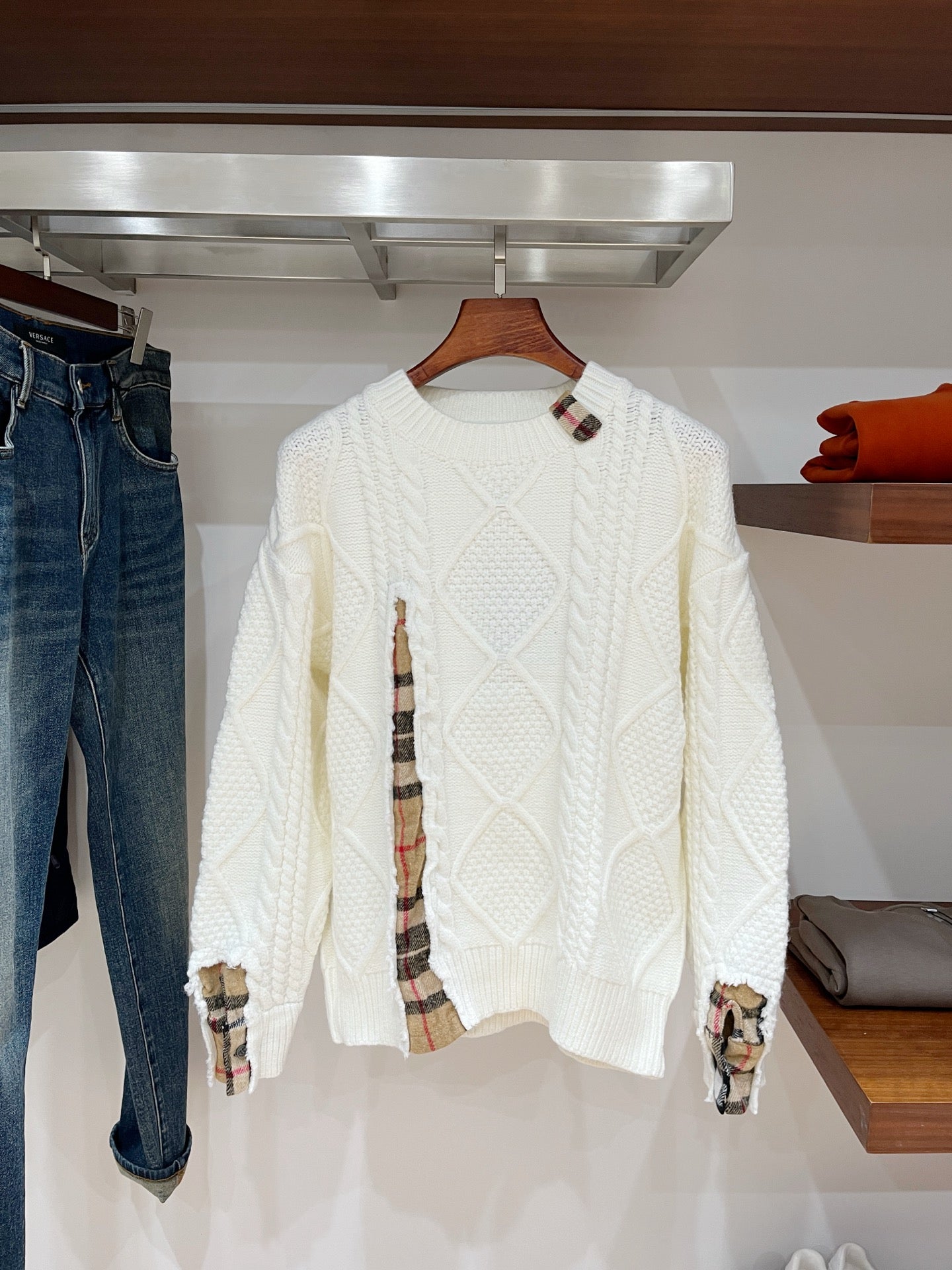 Cream long-sleeve knit sweater with cable-knit pattern and plaid-lined cuffs at sleeves