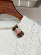 Cream knit sweater detail with ribbed cuffs and plaid inner trim at shoulder
