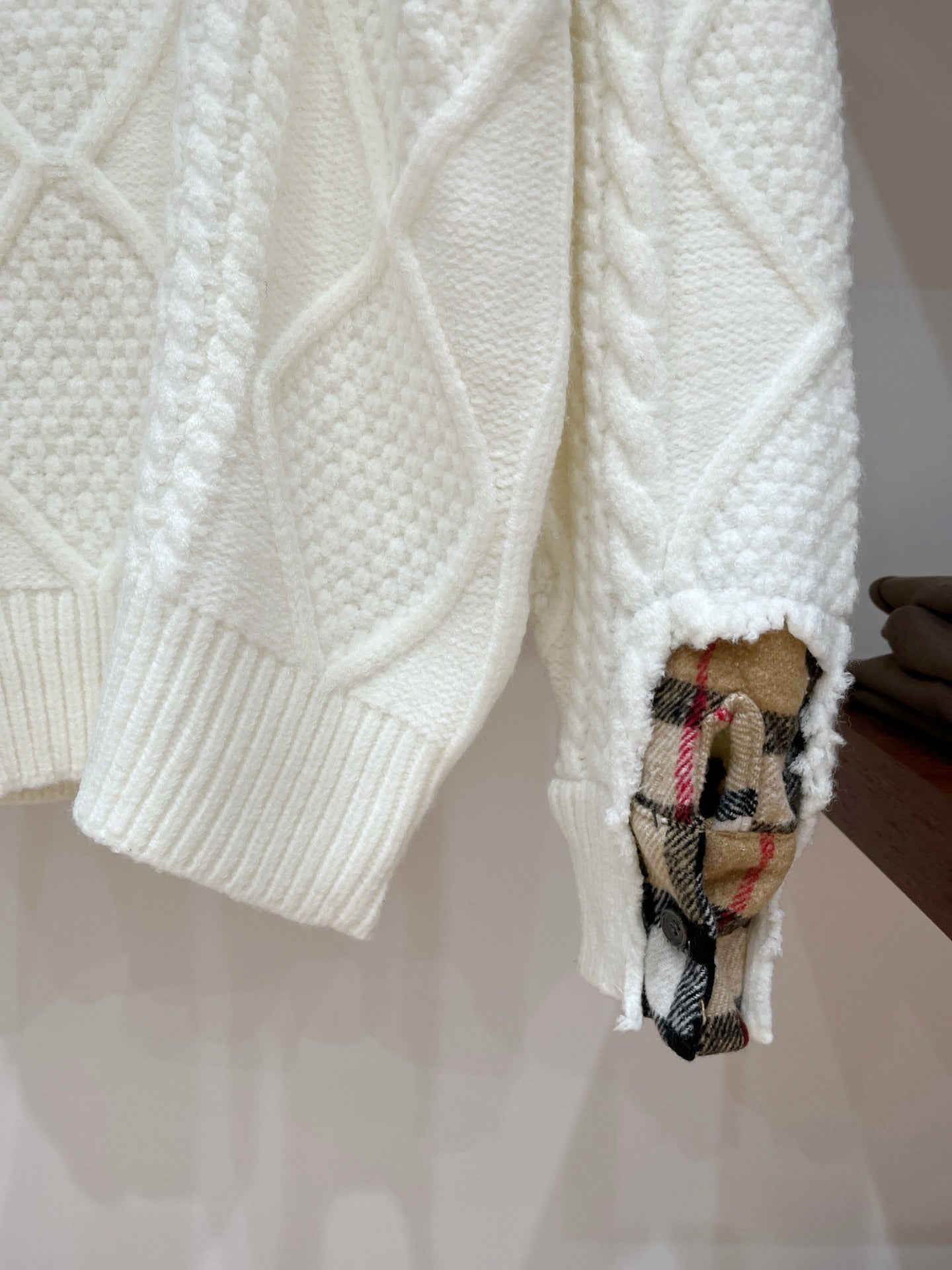 Cream knit sweater sleeves with ribbed cuffs and plaid patch detail at hem