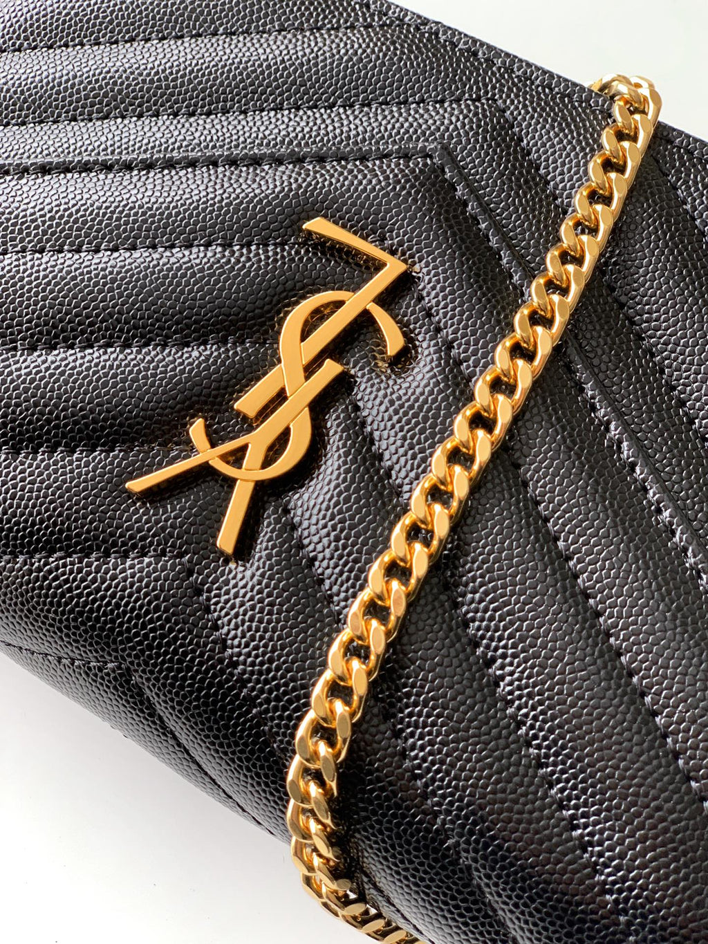 YSL black quilted leather bag close-up with gold YSL monogram and chain