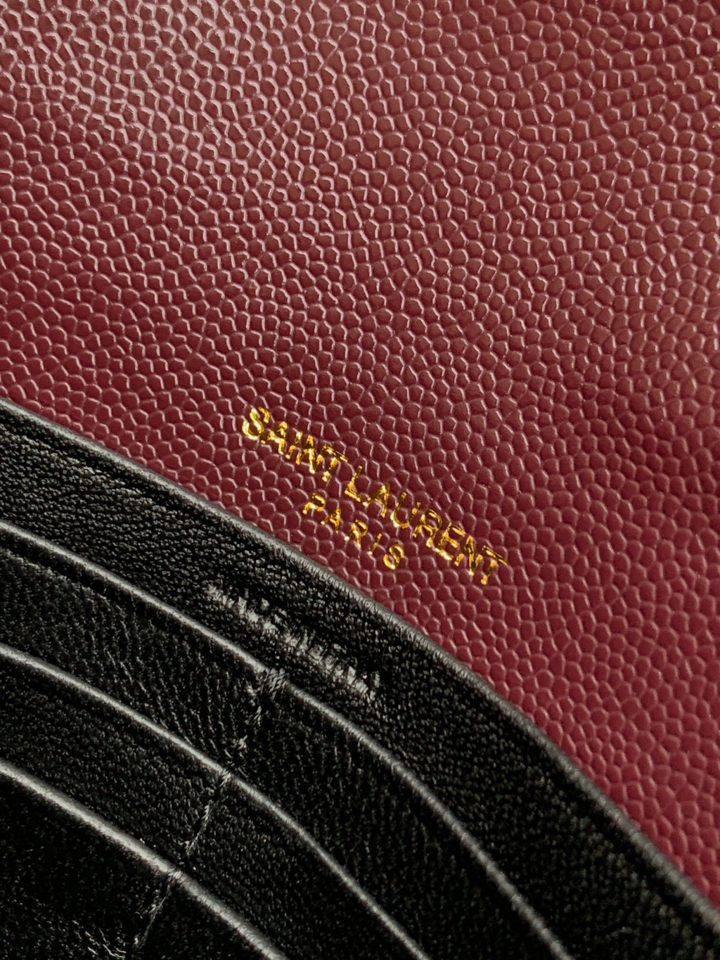 Burgundy textured leather bag with gold YSL lettering on front panel