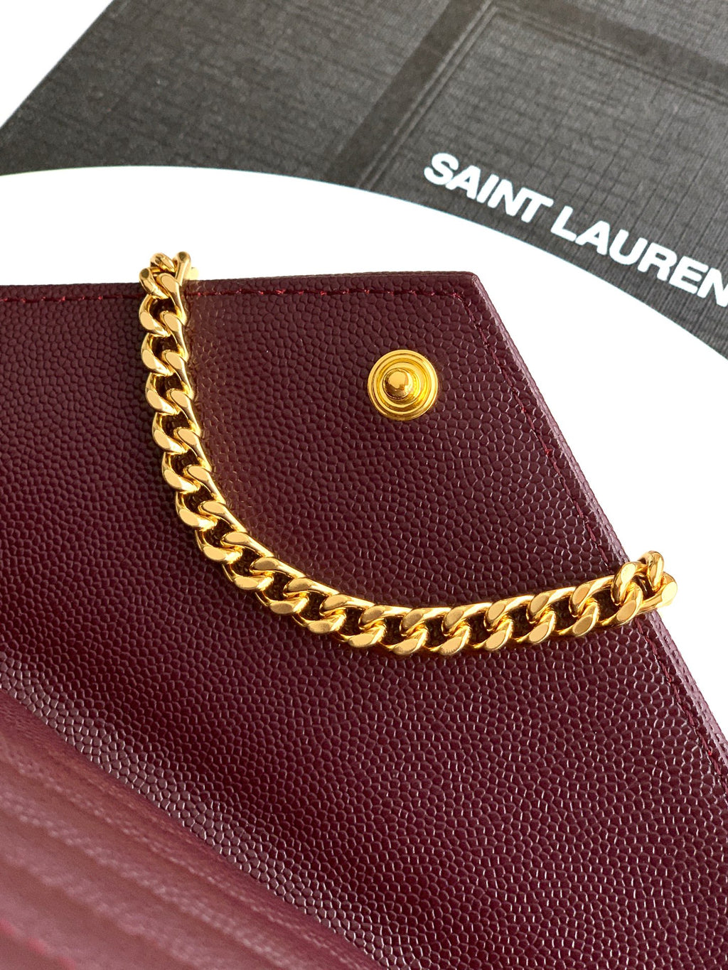 Burgundy flap bag with gold round snap and gold chain shoulder strap