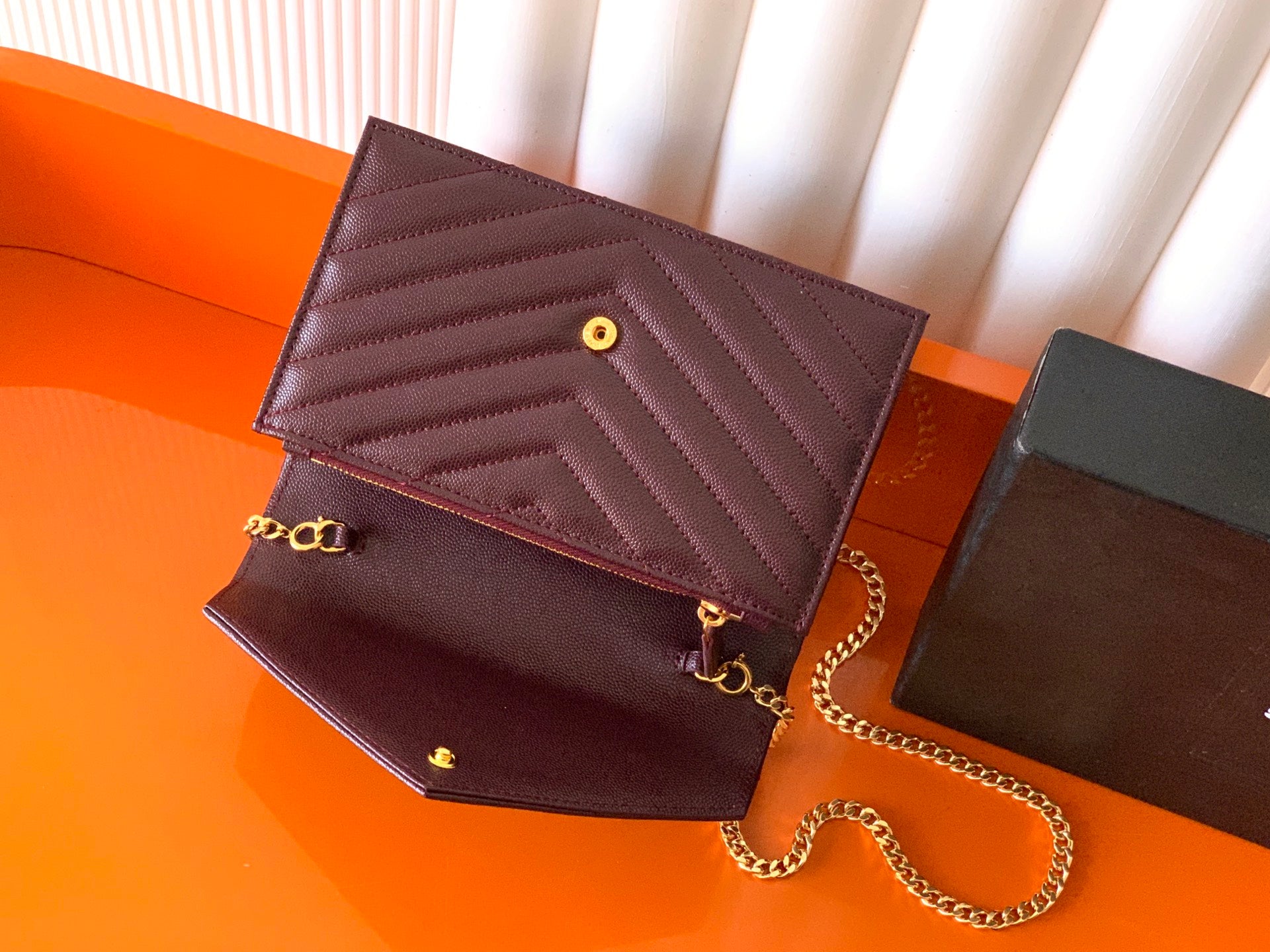 Burgundy flap bag open showing interior, gold hardware, and chain shoulder strap