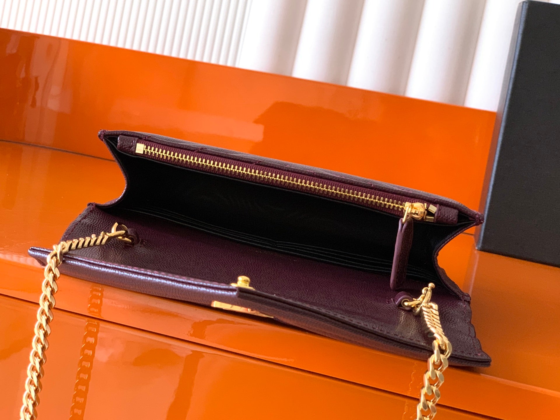 Burgundy flap bag with open top and gold zipper hardware