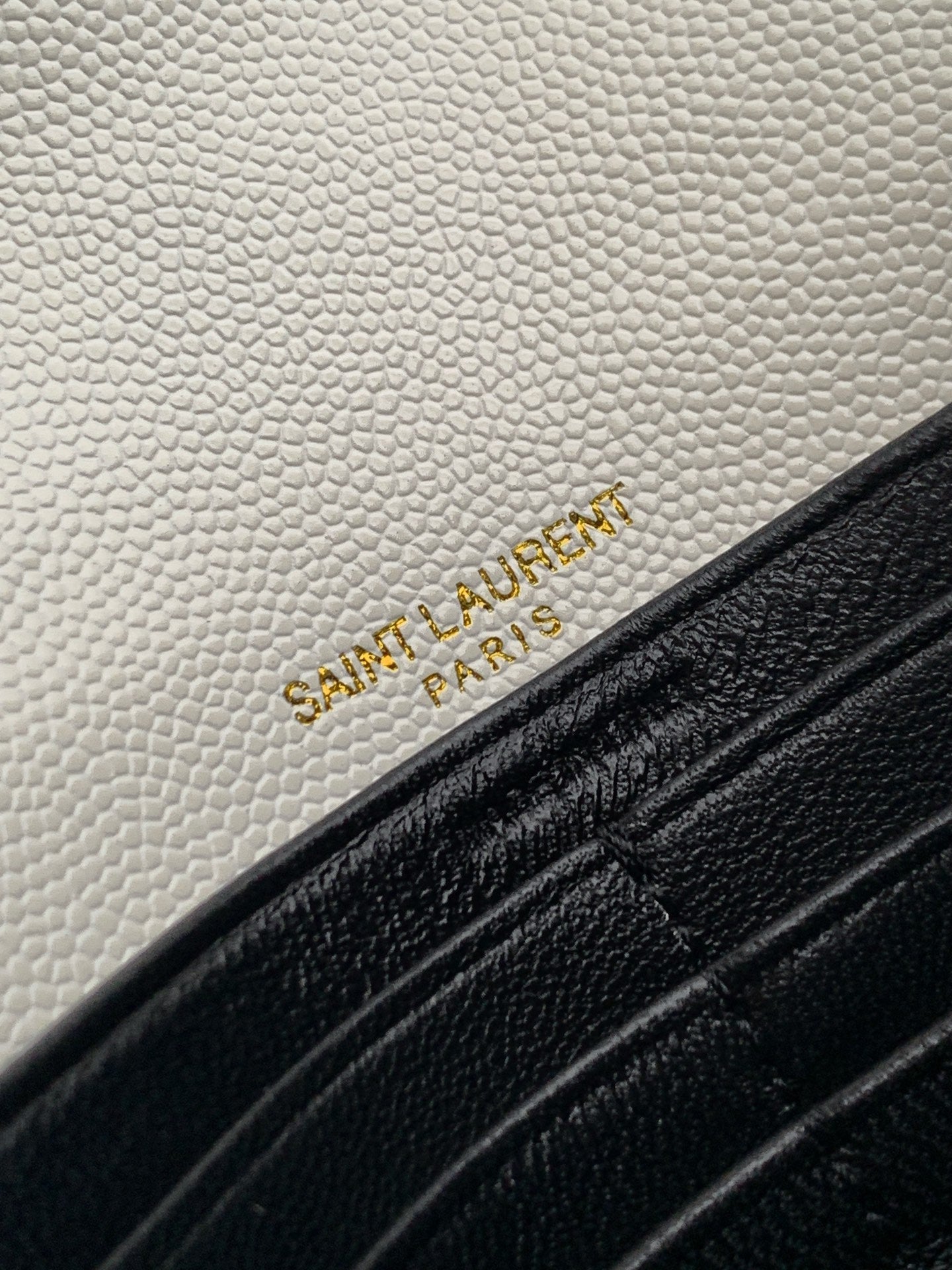 YSL embossed logo on white leather flap with black trim