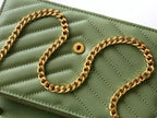 Close-up of green YSL bag front with gold chain and snap button