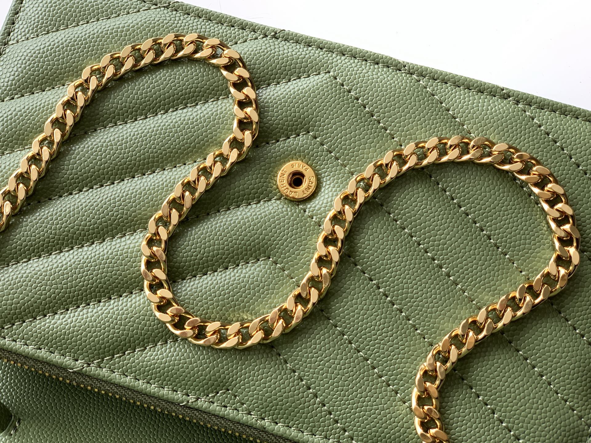 Close-up of green YSL bag front with gold chain and snap button