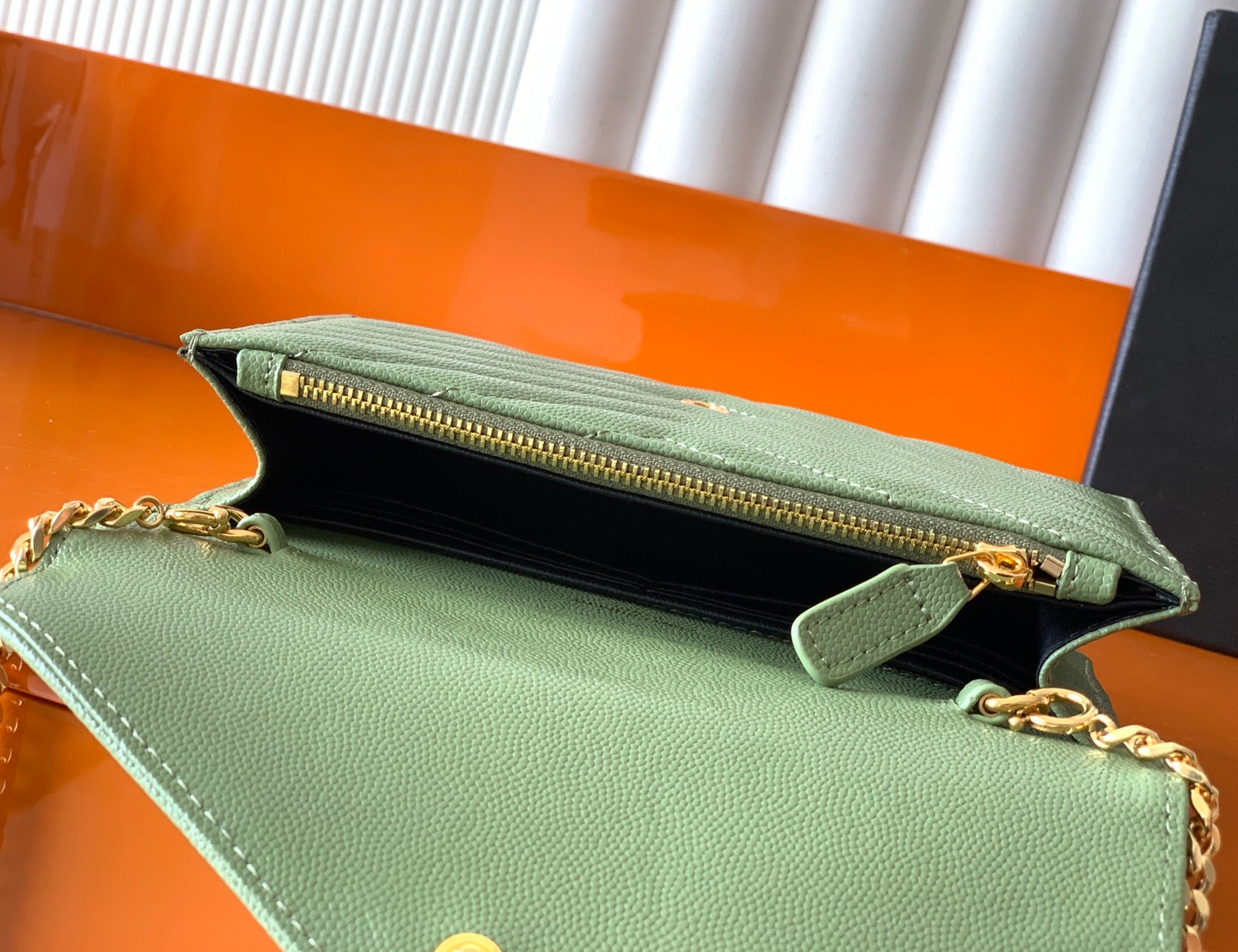 Green YSL bag opened to show black interior and gold zipper