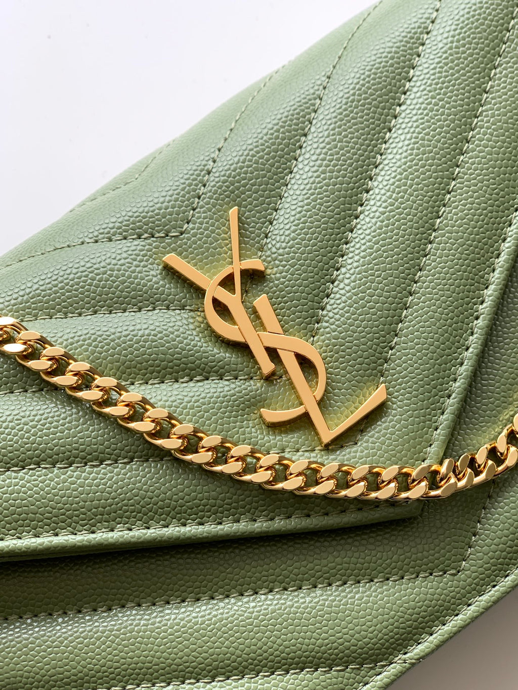Close-up of green quilted YSL flap with gold YSL monogram and chain