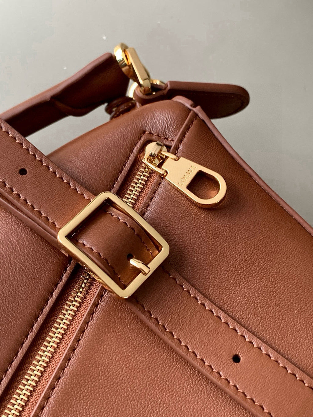 Loewe brown leather bag close-up with buckle strap and gold zipper hardware