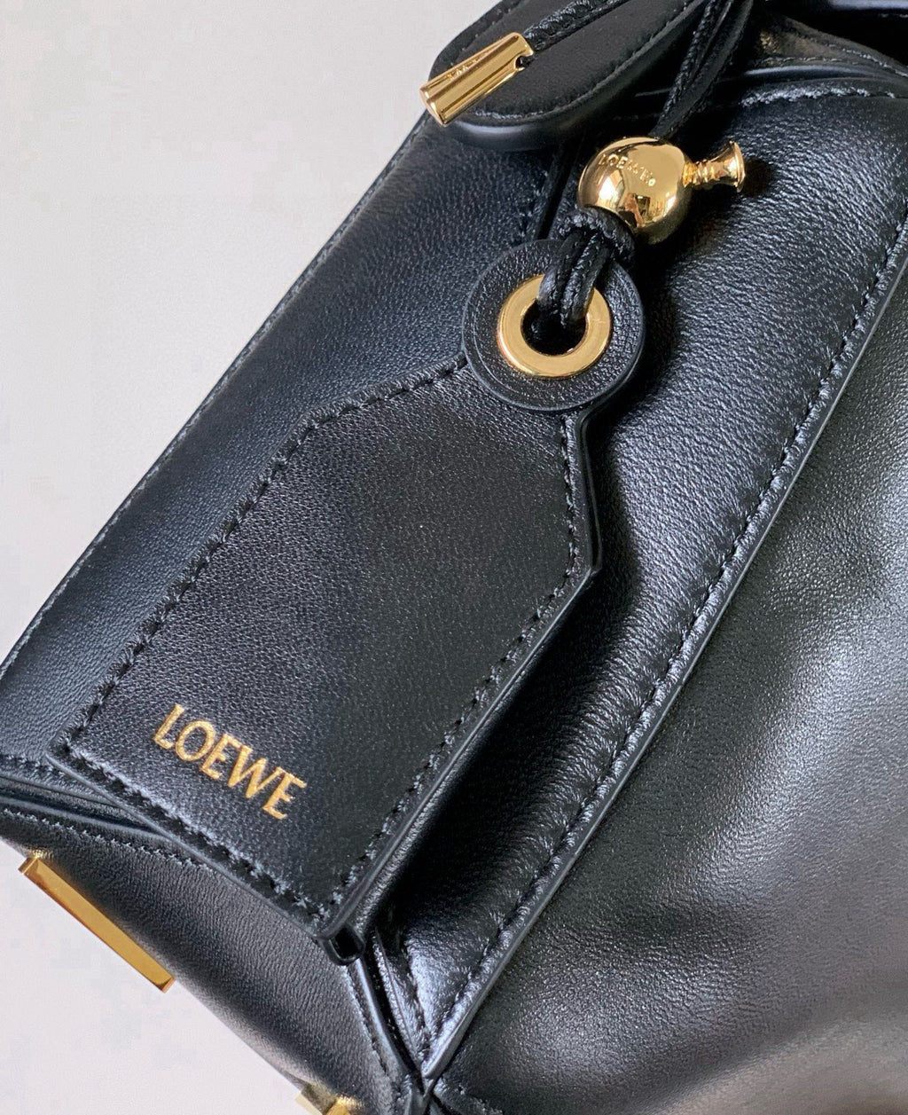 Black leather bag strap with gold-toned ring and Loewe logo patch