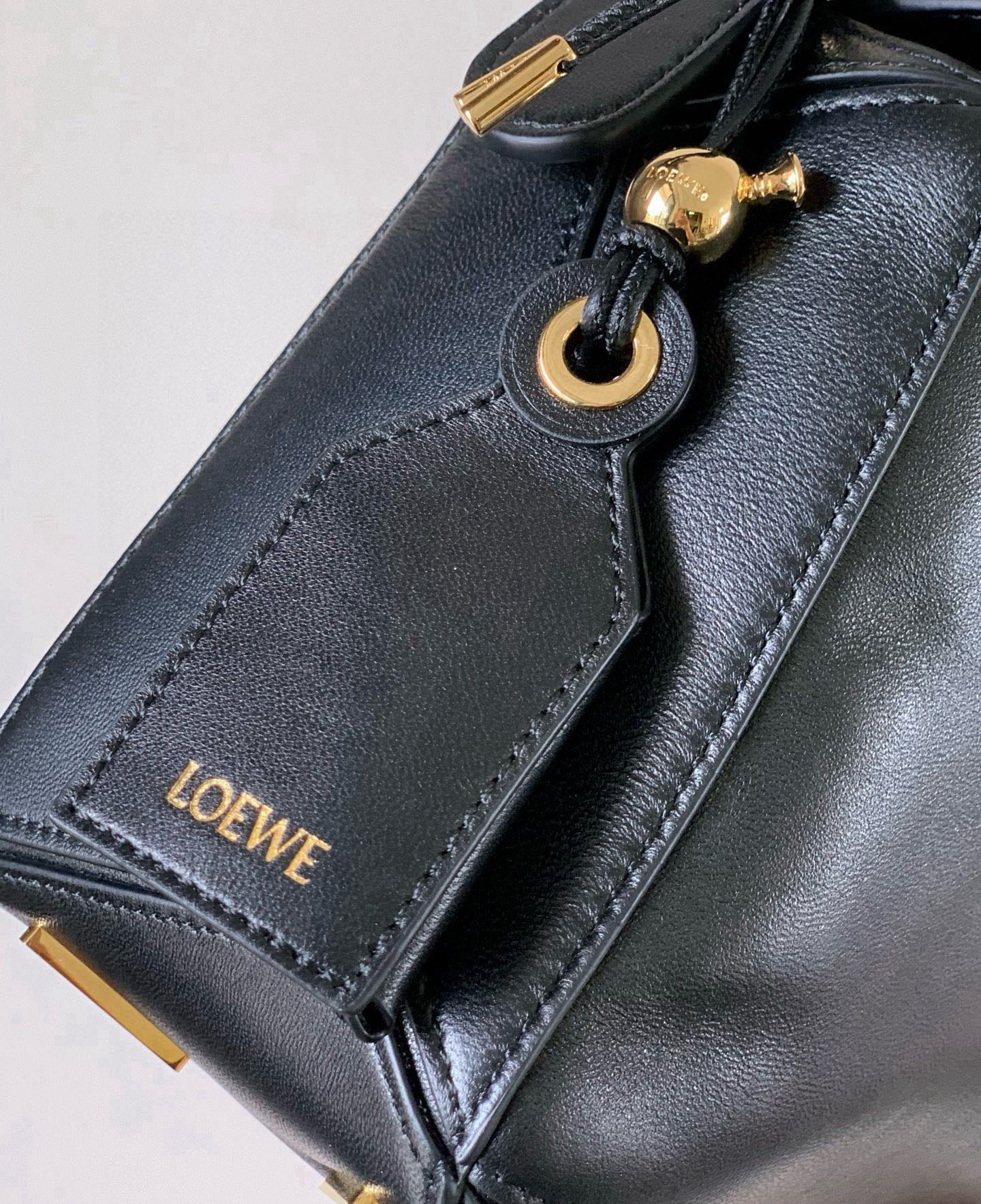Black leather bag strap with gold-toned ring and Loewe logo patch