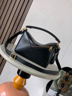 Dark leather shoulder bag with curved handle, crossbody strap, and gold buckles