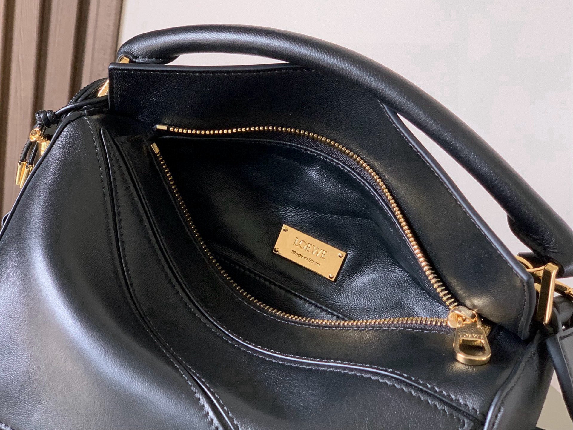 Black leather bag interior with gold zipper pocket and logo label