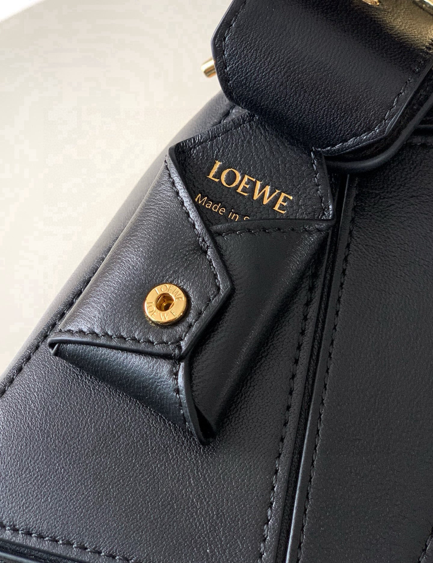 Black leather bag detail with gold button and Loewe logo label