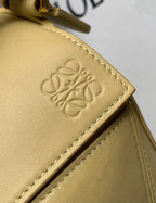 Loewe light yellow leather bag close-up with embossed logo on flap panel