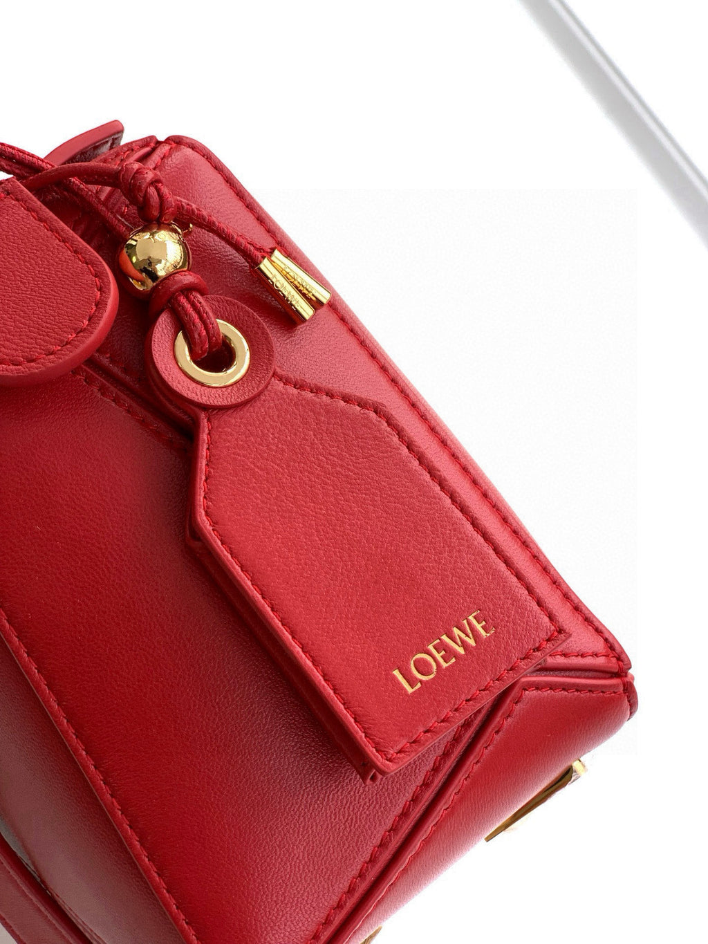 Loewe red leather bag side close-up with Loewe tab and gold ring detail
