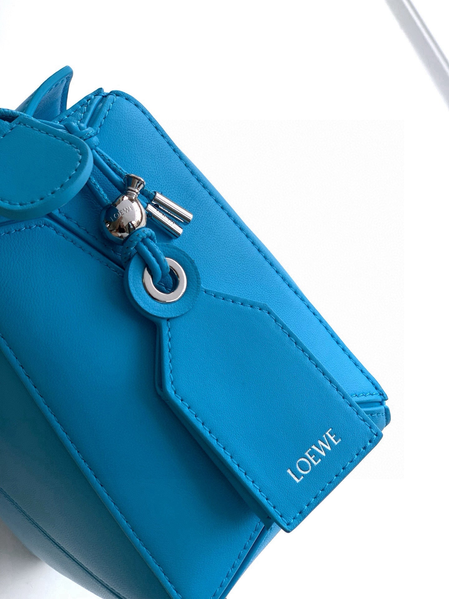 Blue leather bag top detail with metal ring, clasp, and stitched panel