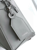 Light gray leather bag side detail with metal ring clasp and stitched panel