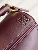 Loewe logo-embossed leather patch on dark burgundy bag near side seam