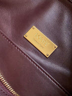 Loewe maroon leather bag close-up with gold LOEWE logo plate on front panel