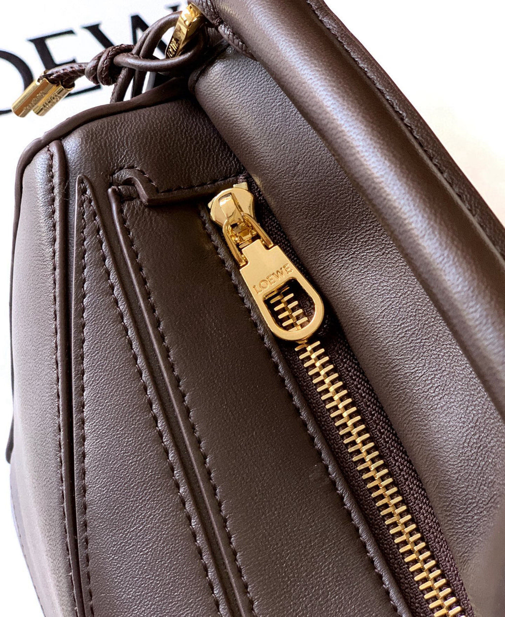Brown leather bag side with gold zipper and stitched panel detail