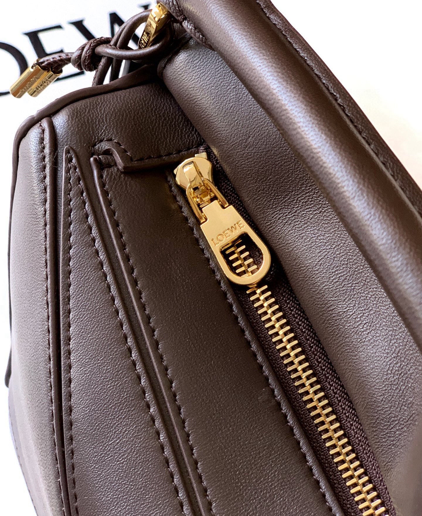 Brown leather bag side with gold zipper and stitched panel detail