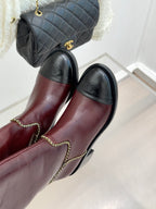 Burgundy knee-high boots with black toe panels and gold chain trim at seams