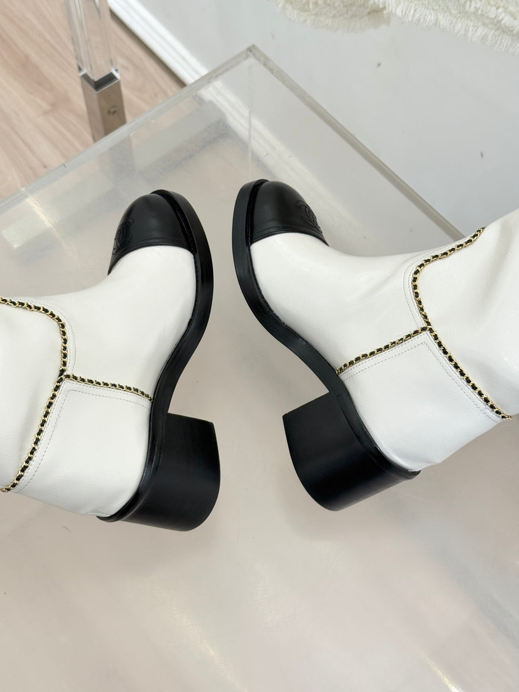 White leather knee boots with black toe panels and gold chain trim, side-by-side
