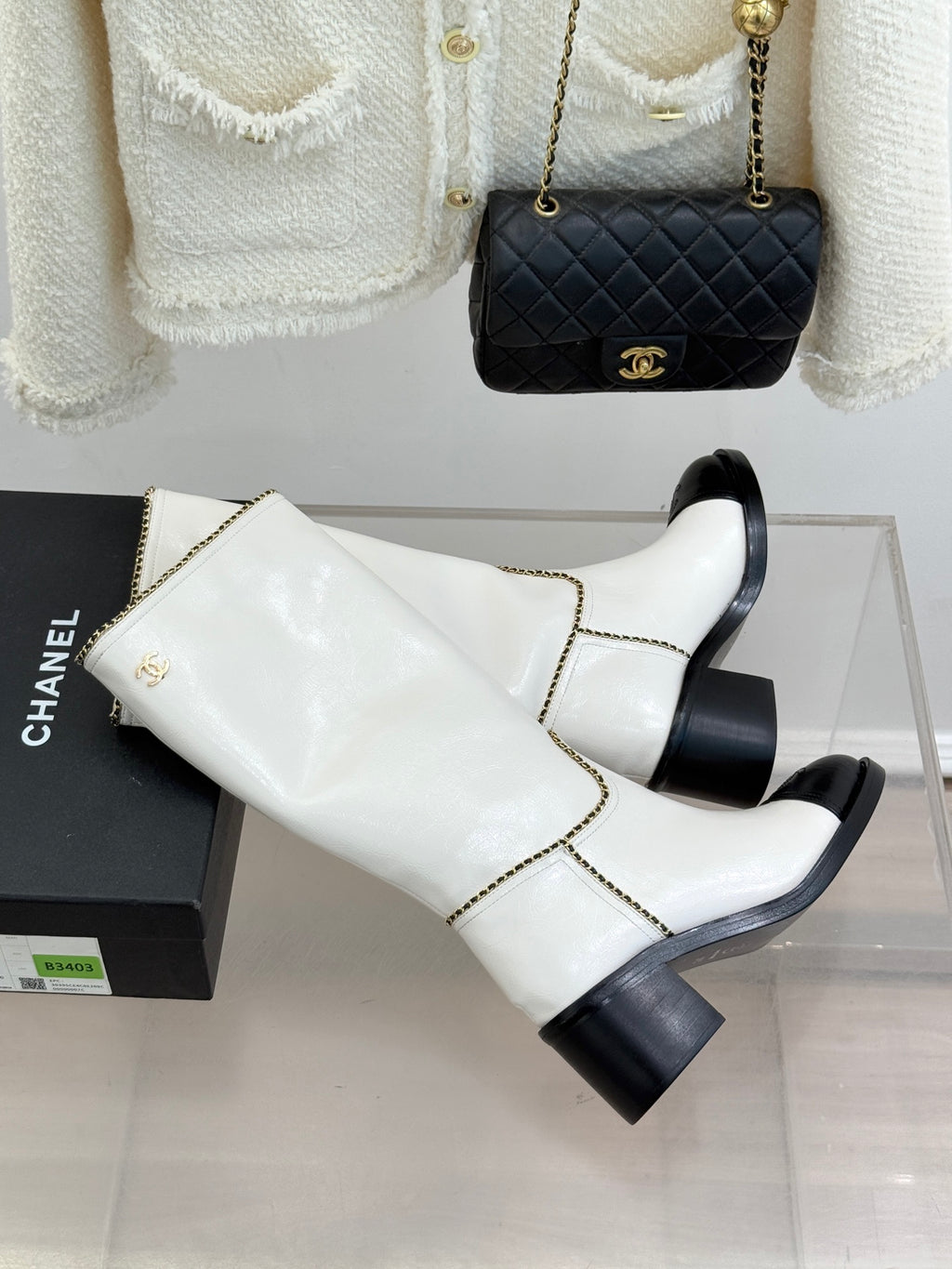 White leather knee boots with black toe panels and gold chain trim, angled side view