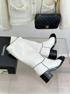 White leather knee boots with black toe panels and gold chain trim, angled side view